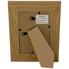 Lade das Bild in den Galerie-Viewer, Back view of a natural wood photo frame with hanging clips and a warning label.