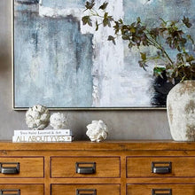 Load image into Gallery viewer, Decorative artichokes in distressed white ceramic on a wooden table with artwork in the background.