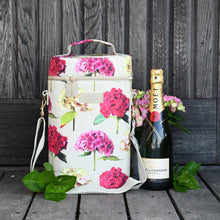 Charger l'image dans la galerie, cooler bag for two bottles in a hydrangea print on a cream background with a bottle standing next to it on a wooden background