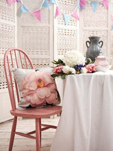 Lade das Bild in den Galerie-Viewer, Botanical cushion featuring Camelia Donation by RHS artist Alfred Wise on a pink chair, beautifully styled with flowers.