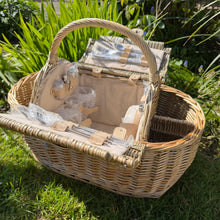 Load image into Gallery viewer, Picnic basket with accessories including utensils, glasses, and cooler, perfect for outdoor dining for four. with a garden background
