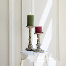 Indlæs billede til gallerivisning Elegant pillar candle holders in an antique finish with green and red candles, perfect for home decor.
