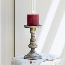 Indlæs billede til gallerivisning Small pillar candle holder in white gold with a red candle, showcasing its elegant and timeless design.
