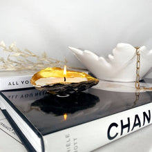 Load image into Gallery viewer, Shell candle in a gold-tipped oyster shell, placed on stylish books for decorative home accents.
