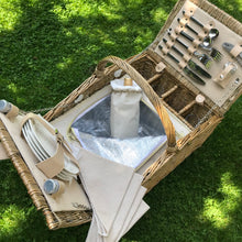 Carica l'immagine nel visualizzatore di Gallery, Deluxe picnic hamper for 4 people with porcelain plates, wine glasses, and cutlery, set on green grass.
